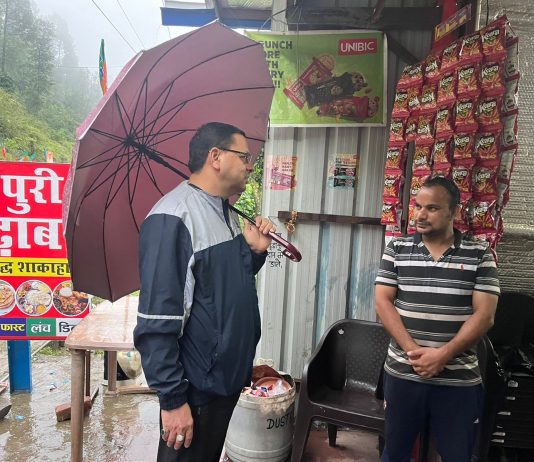 रिमझिम बारिश के बीच छाता लेकर आम लोगों से मिलने पहुंचे सीएम धामी